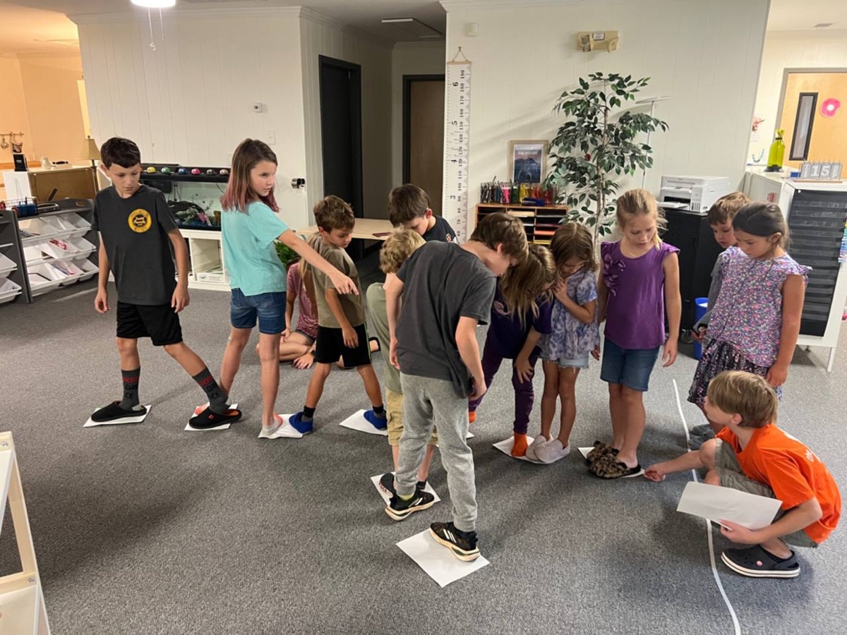 Kids working through a team challenge together at Acton Academy