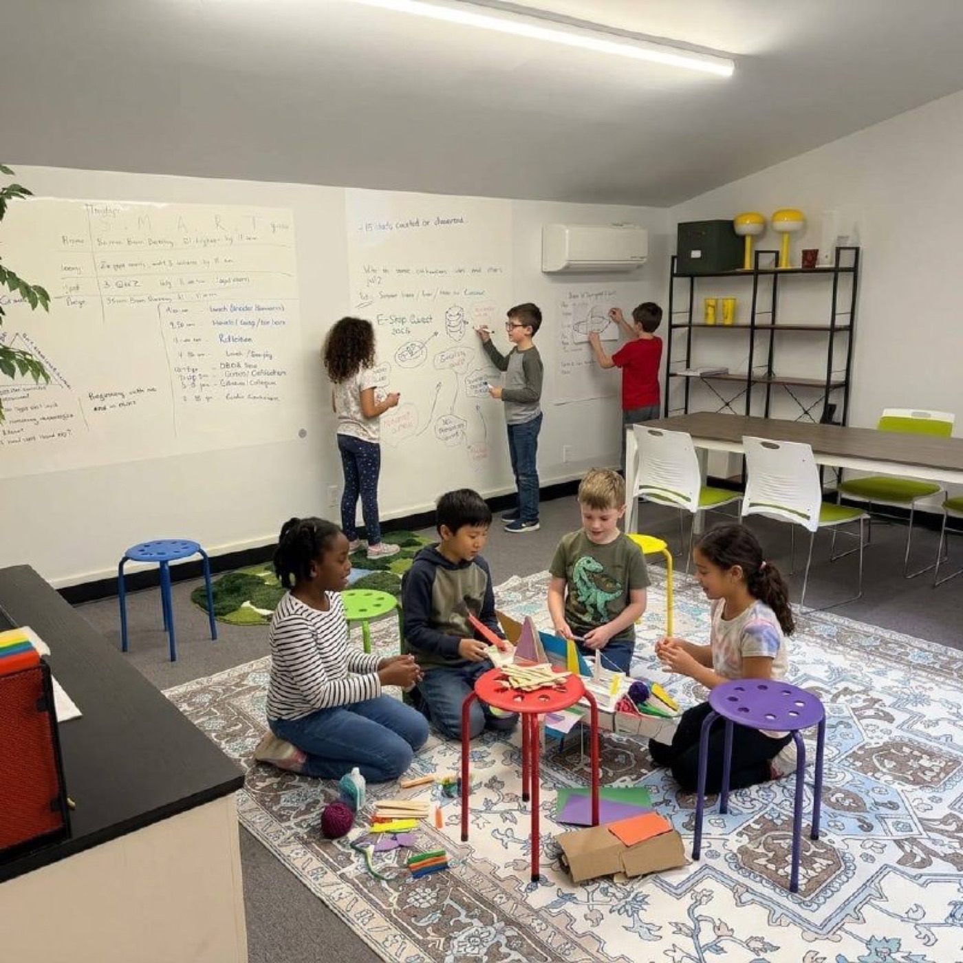 Kids working on whiteboards and floor projects at Acton Academy Ann Arbor